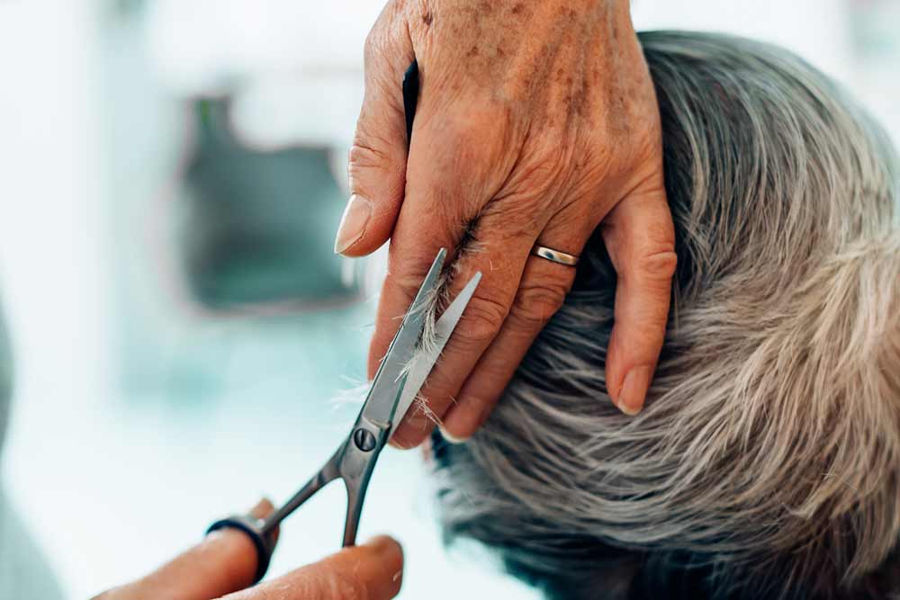 En äldre persons hår blir klippt.
